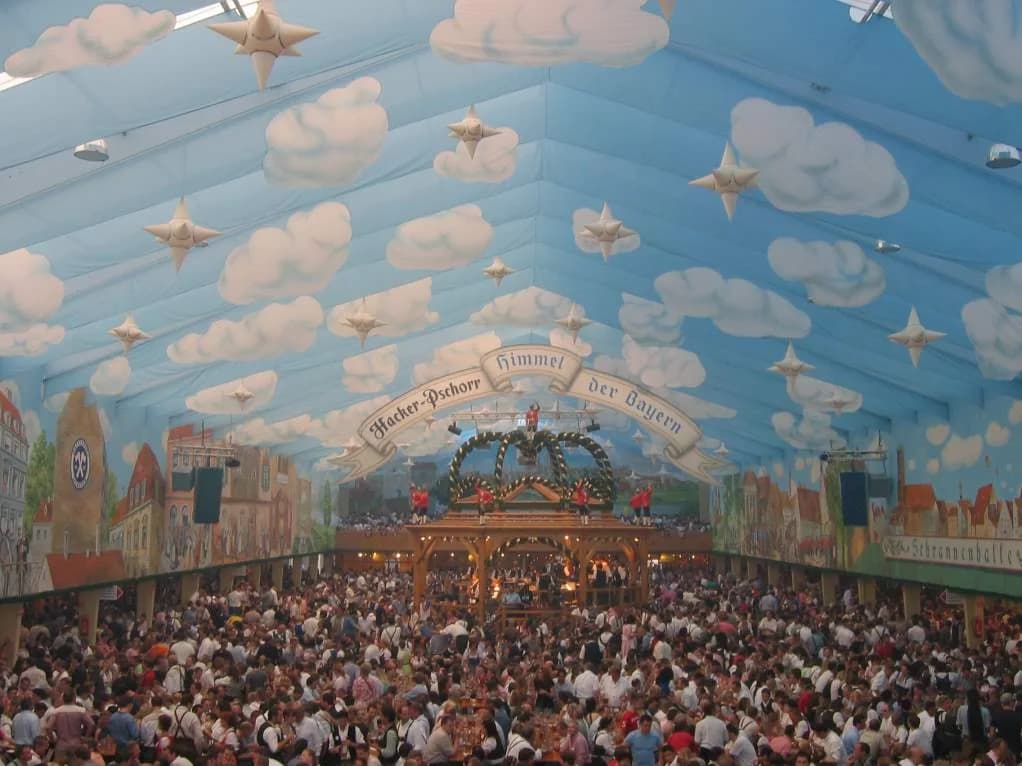 Intérieur de la tente Hacker-Festzelt, avec ses tables et son plafond bleu.
