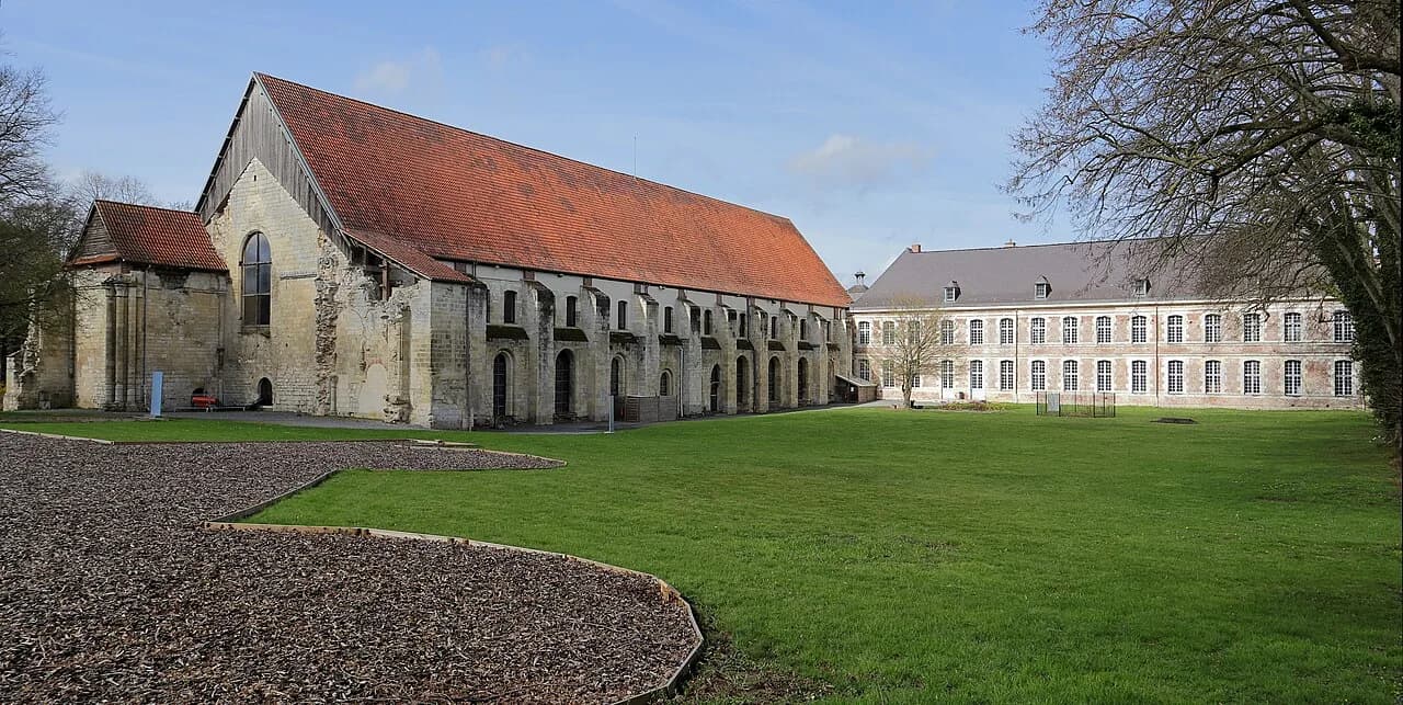 Bâtiments de l’abbaye de Vaucelles et pelouse au premier plan.