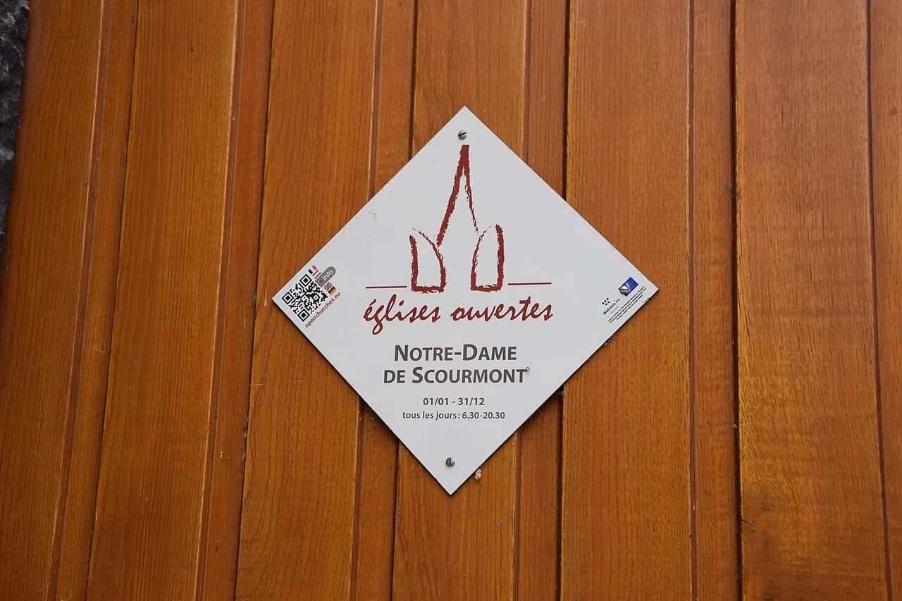 Plaque de l’église Notre-Dame de Scourmont sur une porte en bois.