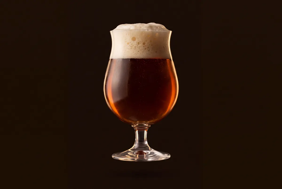 Verre tulipe belge rempli d’une bière ambrée.