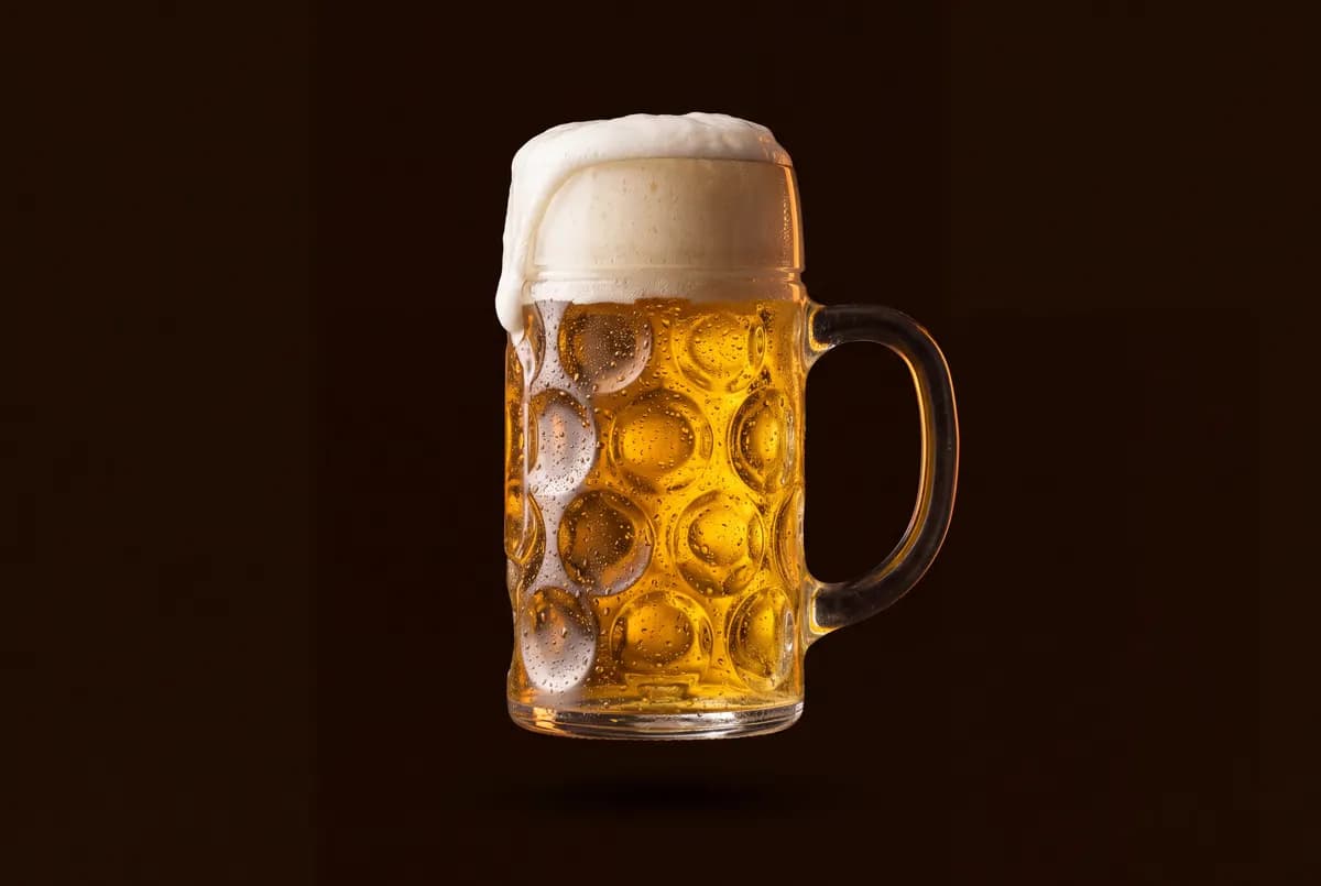 Chope en verre d’un litre remplie de lager dorée, anse épaisse.
